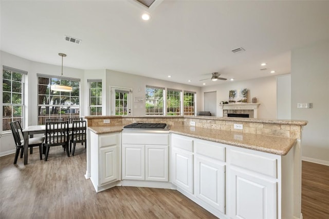 2045 Saint Andrews Dr, Round Rock, TX 78664 - kitchen featuring light wood-style flooring, ceiling fan, a tile fireplace, white cabinets, and recessed lighting