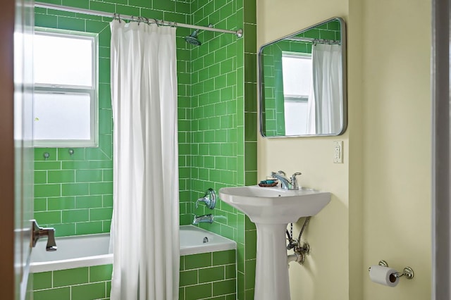 full bathroom with tiled shower / bath combo, a sink, and a wealth of natural light