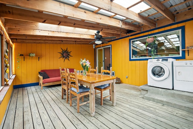dining space featuring wood-type flooring, separate washer and dryer, wood walls, a ceiling fan, and beamed ceiling
