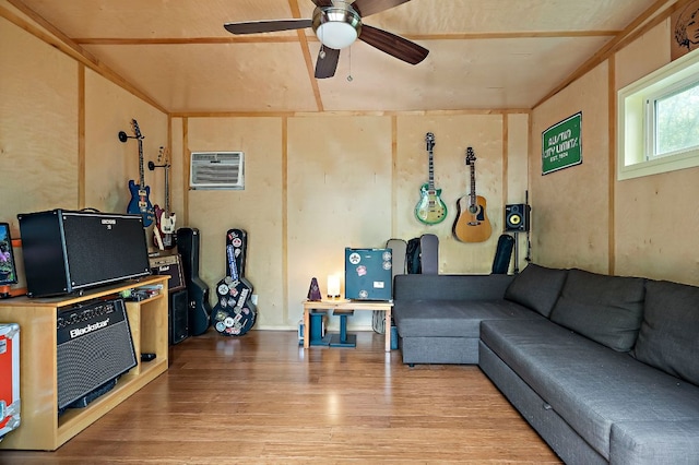 living area with a wall mounted air conditioner, a ceiling fan, and wood finished floors