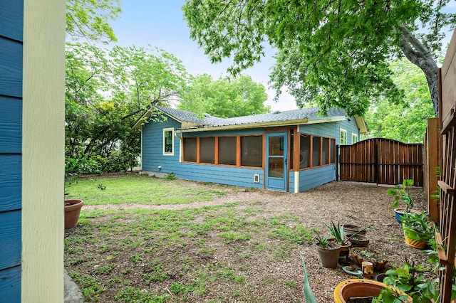 exterior space with a sunroom, a gate, and fence
