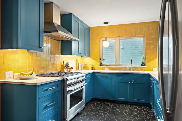 kitchen with a sink, stainless steel appliances, blue cabinetry, and wall chimney exhaust hood