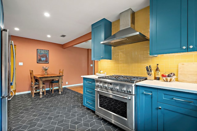 kitchen featuring wall chimney range hood, stainless steel appliances, blue cabinetry, and visible vents