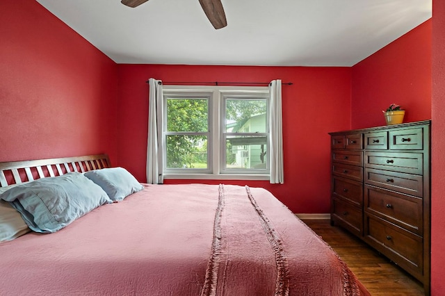 bedroom with a ceiling fan, baseboards, and dark wood-type flooring
