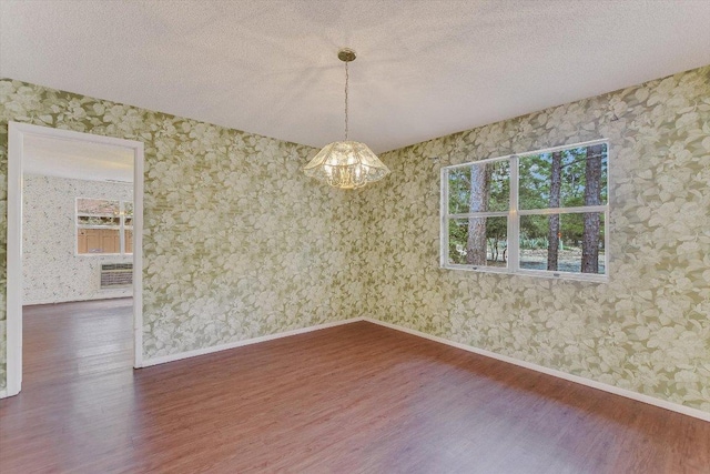 spare room with baseboards, wallpapered walls, plenty of natural light, and wood finished floors