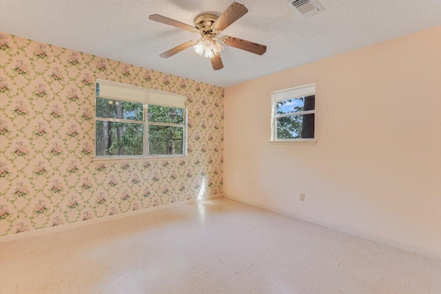 unfurnished room with wallpapered walls, visible vents, and plenty of natural light