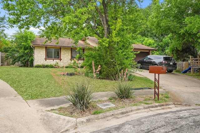 view of front of property featuring fence, stone siding, a garage, a front yard, and driveway