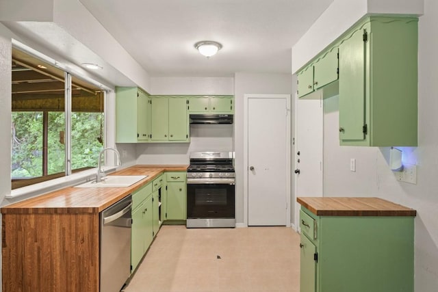 kitchen with appliances with stainless steel finishes, a sink, wood counters, green cabinetry, and under cabinet range hood