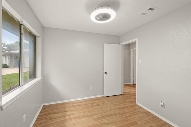 spare room with visible vents, light wood-style flooring, plenty of natural light, and baseboards