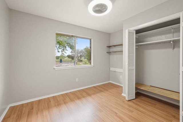 unfurnished bedroom featuring baseboards, wood finished floors, and a closet