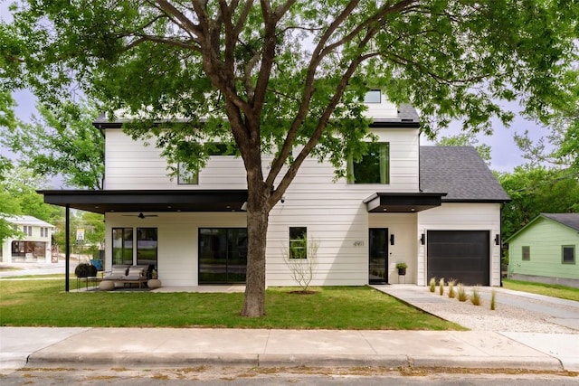 view of front of home with ceiling fan, a front yard, a garage, concrete driveway, and a patio