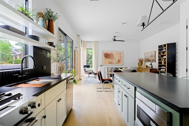 kitchen with ceiling fan, dark countertops, a sink, open floor plan, and stainless steel appliances