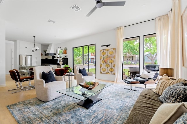 living area with light wood-style floors, a ceiling fan, and visible vents