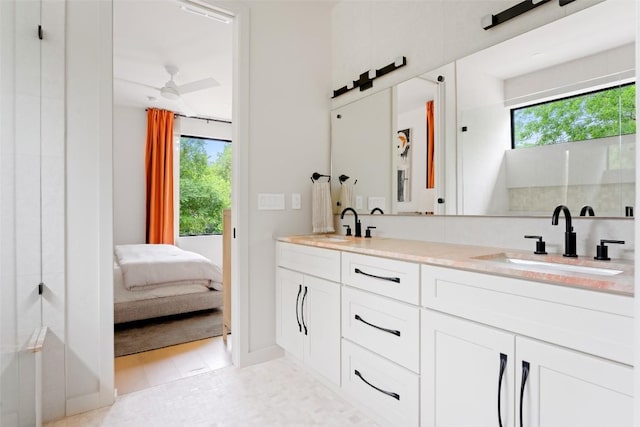 ensuite bathroom with double vanity, a sink, and a healthy amount of sunlight