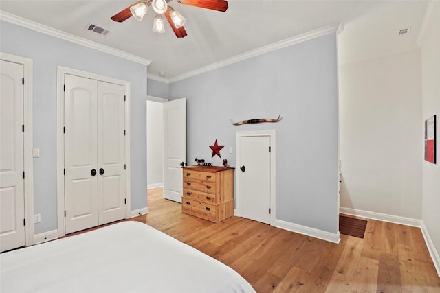 bedroom with baseboards, ornamental molding, wood finished floors, and visible vents