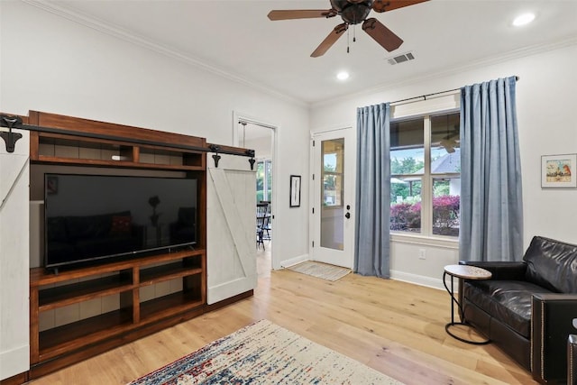 living area with visible vents, ornamental molding, baseboards, light wood-type flooring, and a ceiling fan