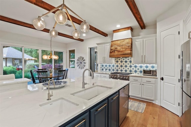 kitchen with white cabinets, stainless steel appliances, beam ceiling, and a sink