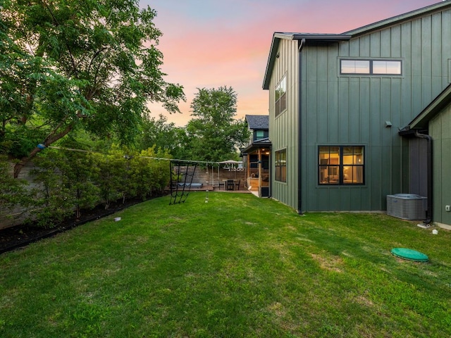 back of house with a lawn, board and batten siding, and cooling unit
