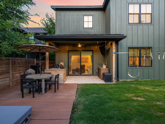 back of house with fence, a wooden deck, board and batten siding, area for grilling, and a yard