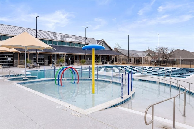 pool featuring fence, a patio area, and a water play area