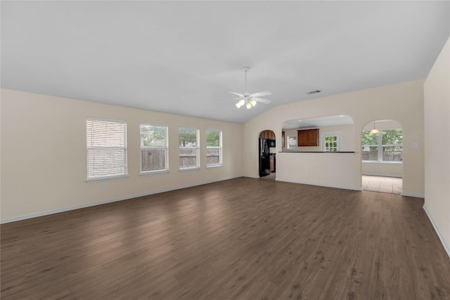 unfurnished living room with visible vents, baseboards, ceiling fan, arched walkways, and dark wood finished floors