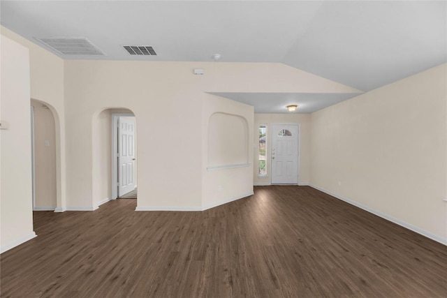 unfurnished room featuring visible vents, arched walkways, lofted ceiling, and dark wood-style floors
