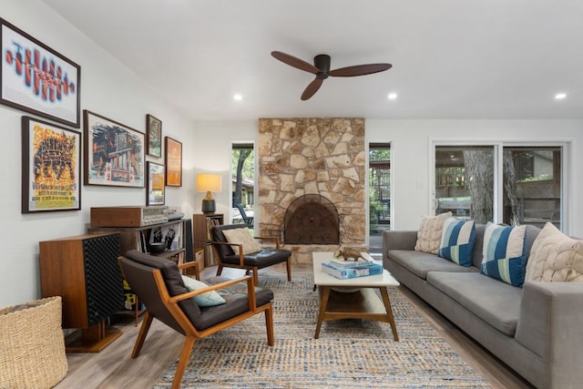 living room with recessed lighting, ceiling fan, wood finished floors, and a stone fireplace