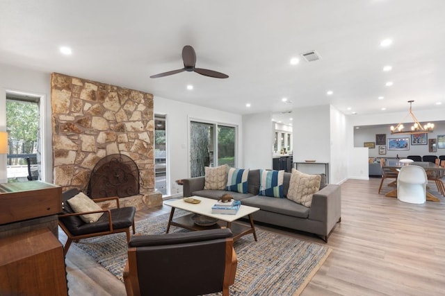 living room with visible vents, a healthy amount of sunlight, a stone fireplace, and light wood-type flooring