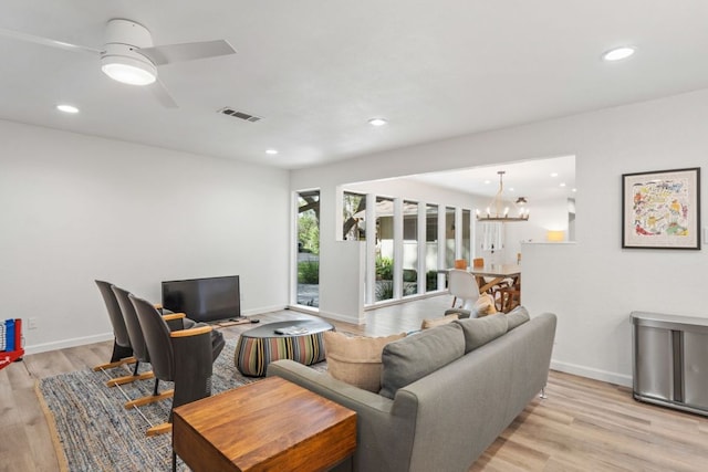 living room featuring recessed lighting, ceiling fan with notable chandelier, light wood finished floors, and visible vents