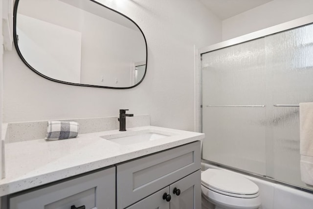 bathroom with vanity, enclosed tub / shower combo, and toilet