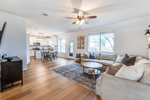 living area with visible vents, light wood-style flooring, and ceiling fan