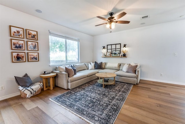 living room with a ceiling fan, baseboards, visible vents, and wood finished floors