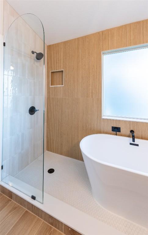 bathroom with a soaking tub and tiled shower