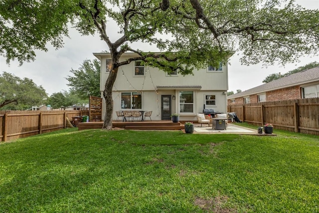 back of house featuring a fenced backyard, a wooden deck, a lawn, and a patio
