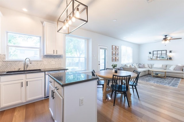 kitchen featuring dark countertops, a sink, light wood-style floors, tasteful backsplash, and a kitchen island