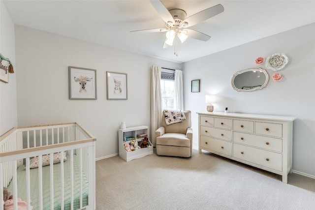 bedroom featuring a nursery area, a ceiling fan, baseboards, and carpet