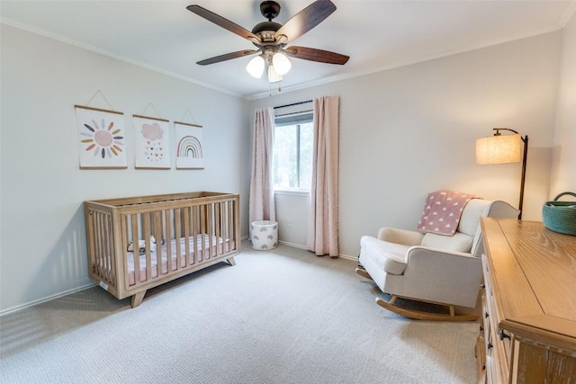 bedroom with ornamental molding, baseboards, ceiling fan, a crib, and carpet flooring