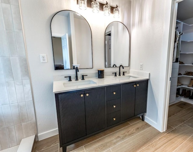 full bathroom with baseboards, a sink, and wood finished floors