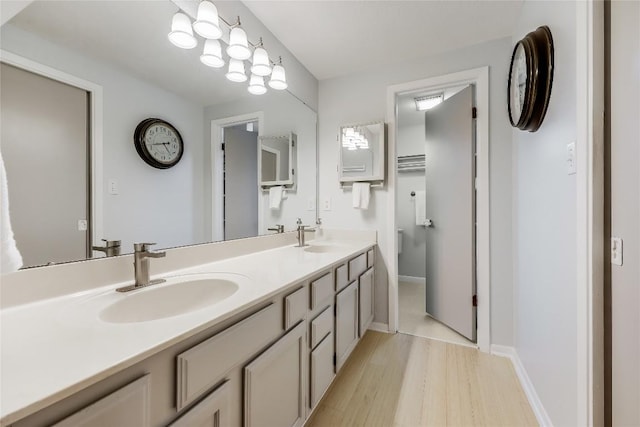 bathroom featuring double vanity, a sink, baseboards, and wood finished floors