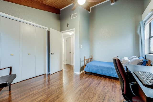 bedroom with visible vents, a closet, wood finished floors, beamed ceiling, and wood ceiling
