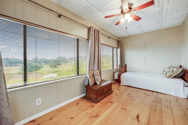 bedroom with light wood-type flooring, a ceiling fan, and an ornate ceiling