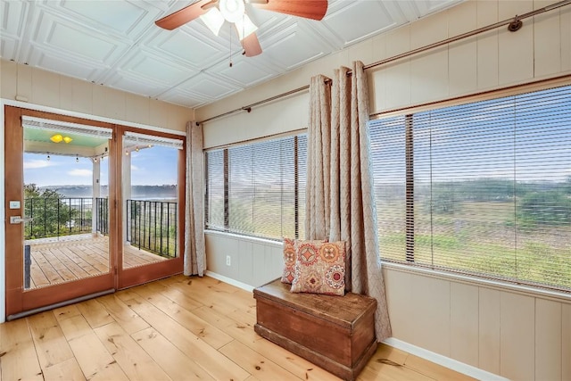 sunroom / solarium featuring baseboards, wooden walls, and hardwood / wood-style flooring