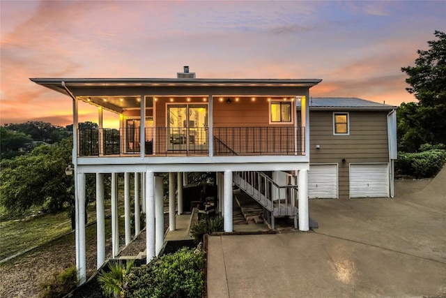back of property featuring concrete driveway, stairs, and a garage