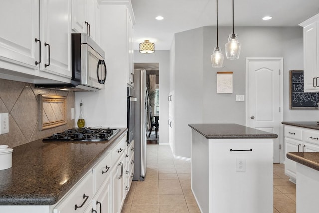 kitchen with appliances with stainless steel finishes, a center island, white cabinetry, decorative backsplash, and light tile patterned floors