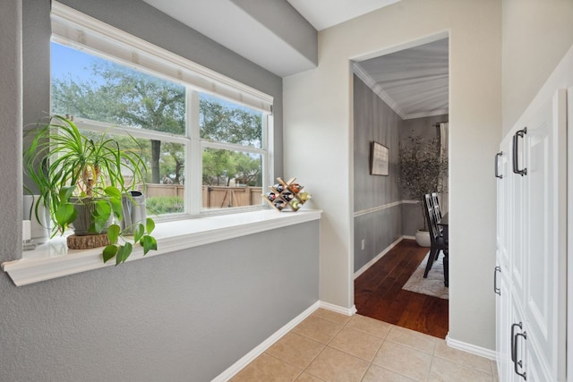 hallway featuring baseboards, light tile patterned flooring, and a wealth of natural light