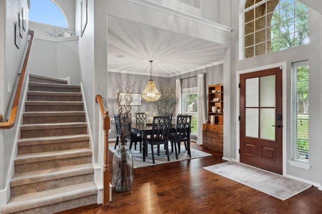 foyer entrance with crown molding, stairway, and dark wood-type flooring
