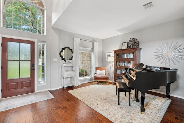 foyer entrance with baseboards, dark wood finished floors, and visible vents