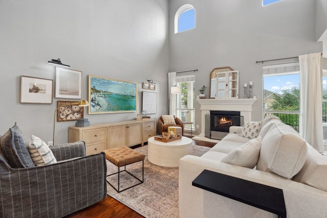 living area featuring a glass covered fireplace, a towering ceiling, and dark wood-style floors