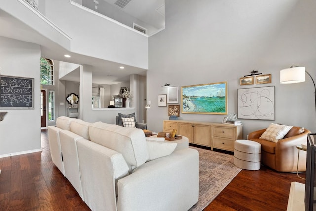 living area with visible vents, dark wood-style floors, and a towering ceiling