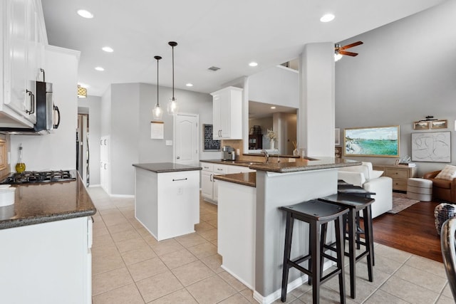 kitchen with light tile patterned flooring, a sink, a center island, a ceiling fan, and stainless steel appliances